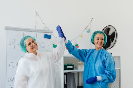 Two healthcare professionals in PPE high-fiving in a lab, exuding positivity.