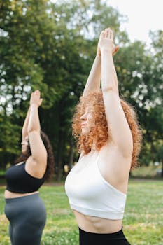 Two women practicing yoga outdoors in a park, focusing on wellness and fitness.