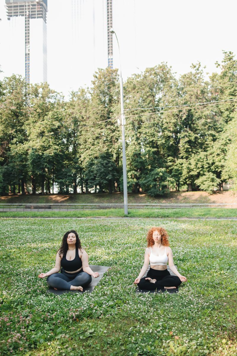 Two women meditating outdoors on the grass
