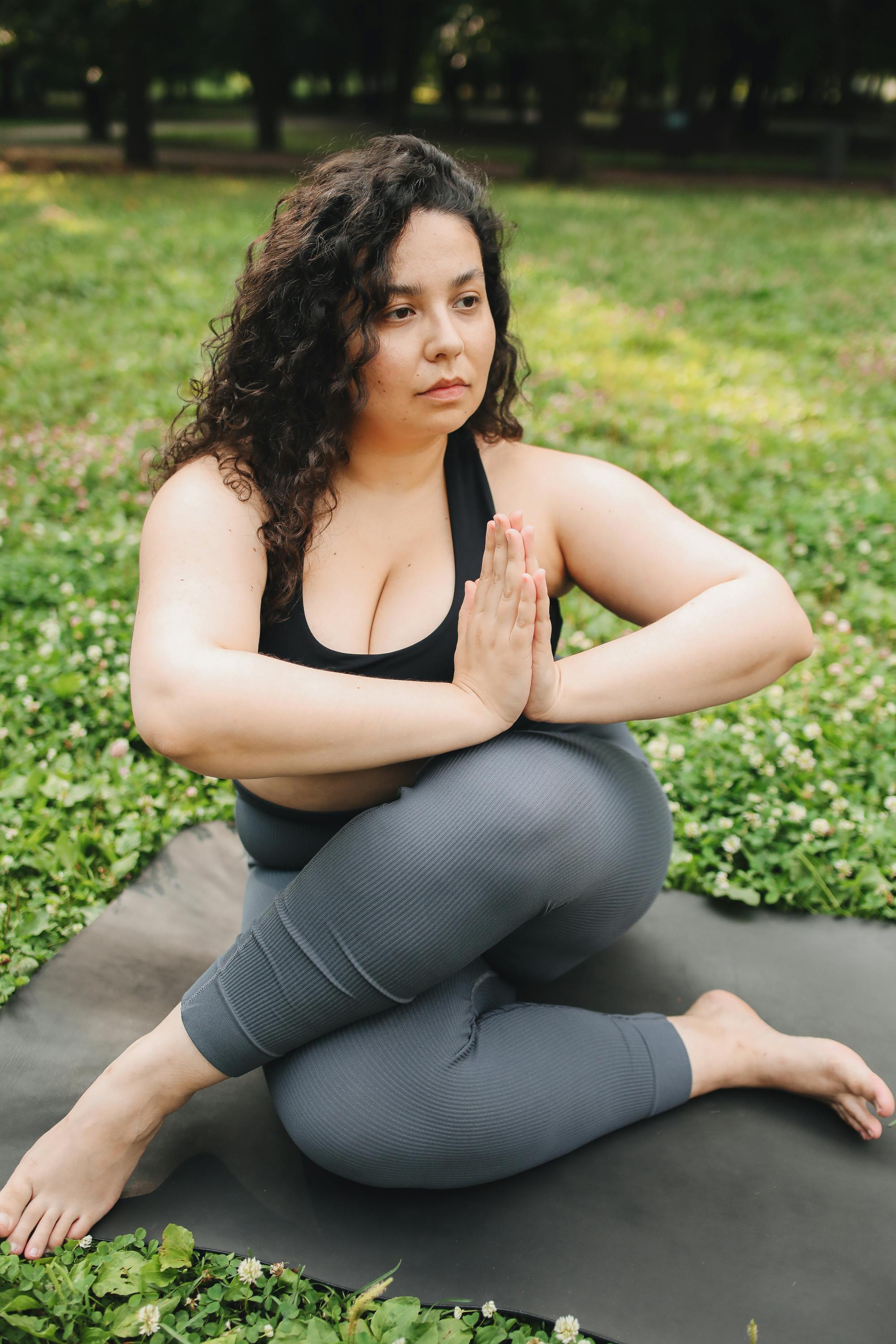 Young slim blonde female in black sportswear doing yoga asana on blue mat  on wooden balcony with green trees in background - Stock Image - Everypixel