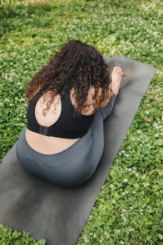 Plus-size woman practicing yoga outdoors on a mat, promoting fitness and relaxation.