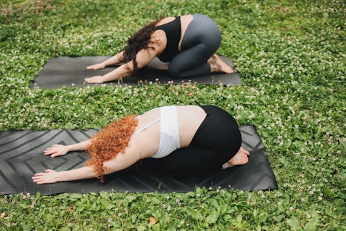 Free Two Women Practicing Yoga on Green Grass Stock Photo