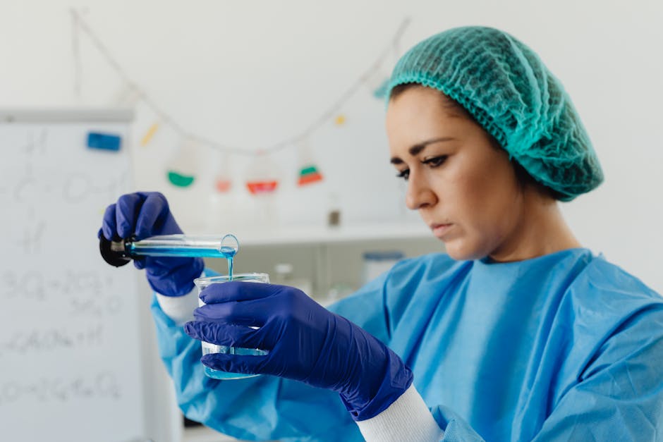 Focused female scientist in lab gear performing liquid analysis experiment.