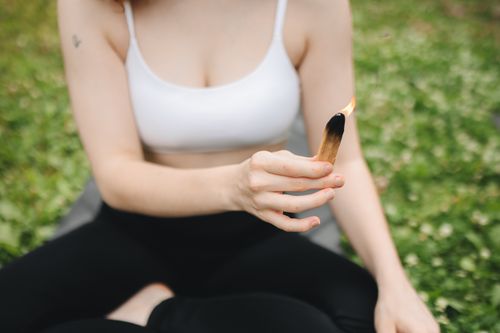 Free Woman holding burning stick during yoga practice on green grass outdoors, promoting calm and mindfulness. Stock Photo