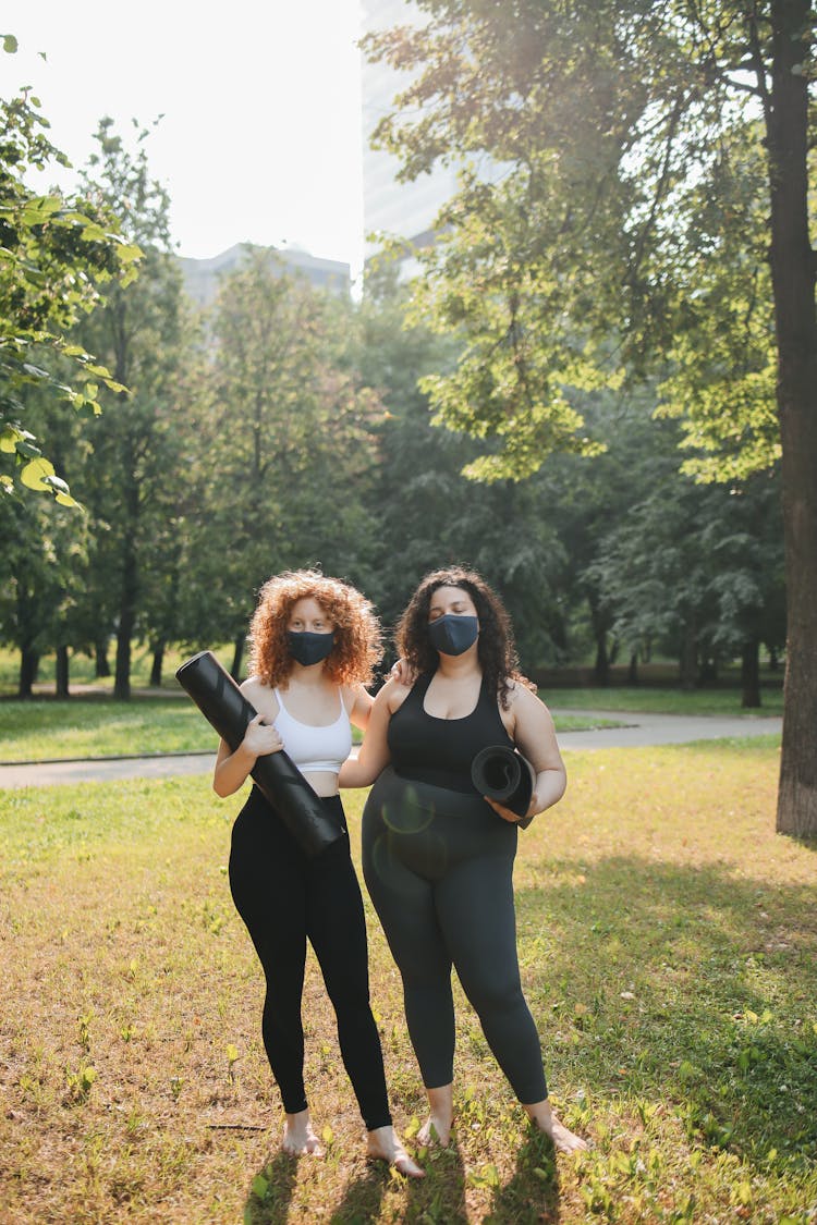 Woman Holding Black Yoga Mats Standing On The Park