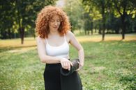 Woman in White Tank Top and Black Skirt Standing on Green Grass Field