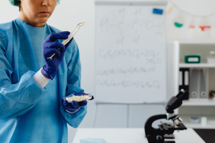 Woman Holding A Pill Using Tweezers