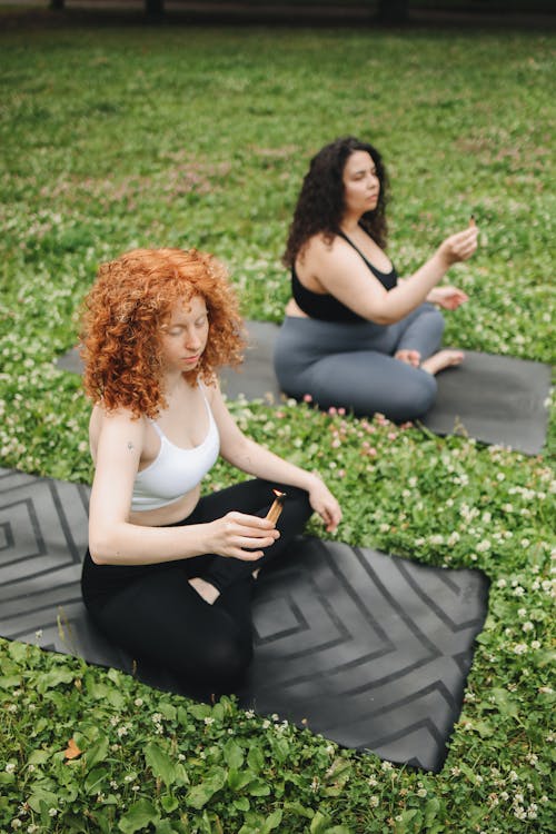 Free Women Sitting on Yoga Mat Holding a Burning Dried Leaf Stock Photo