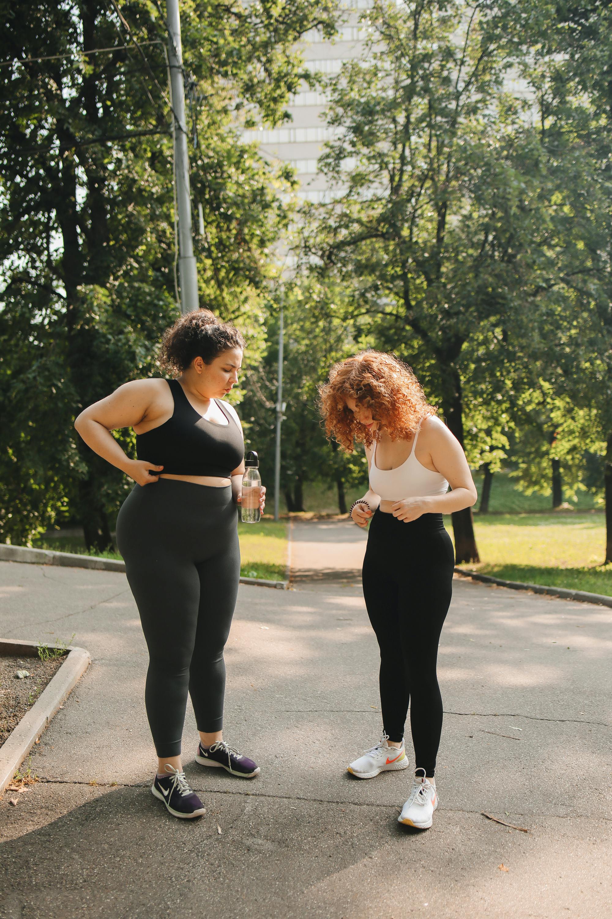 women wearing tank tops and leggings standing on walkway