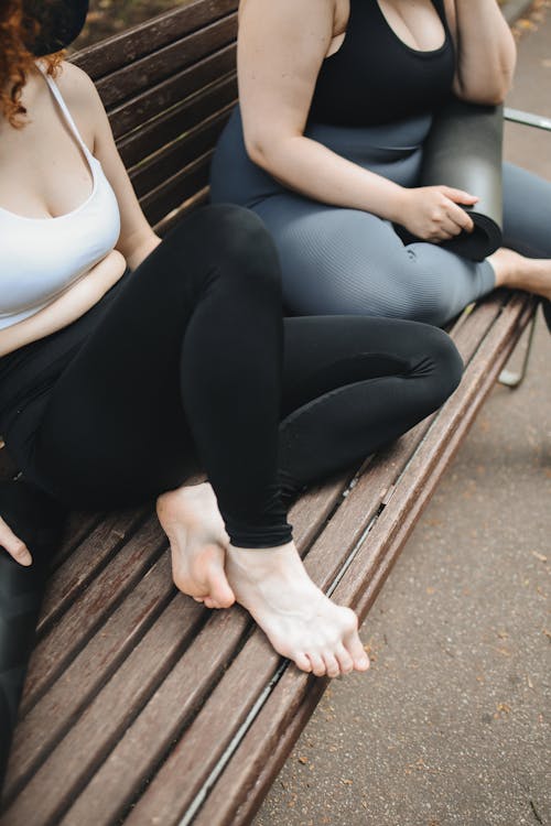 Women in Active Wear Sitting on a Wooden Bench