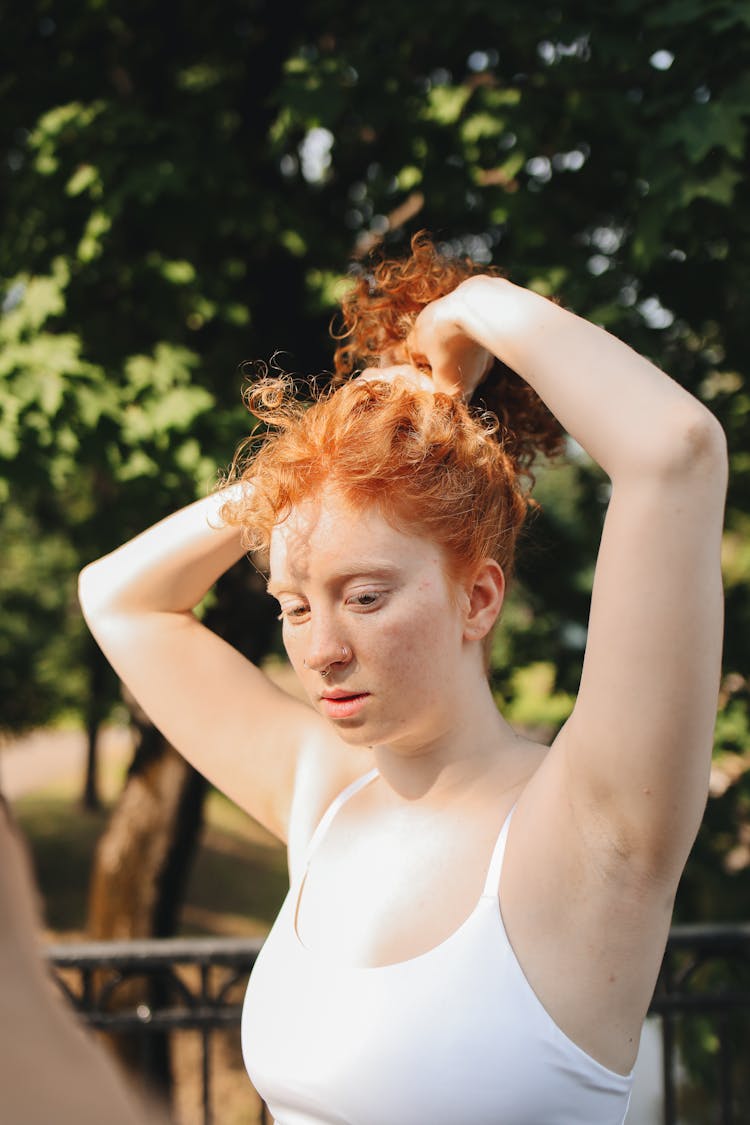 Woman In White Top Tying Her Hair