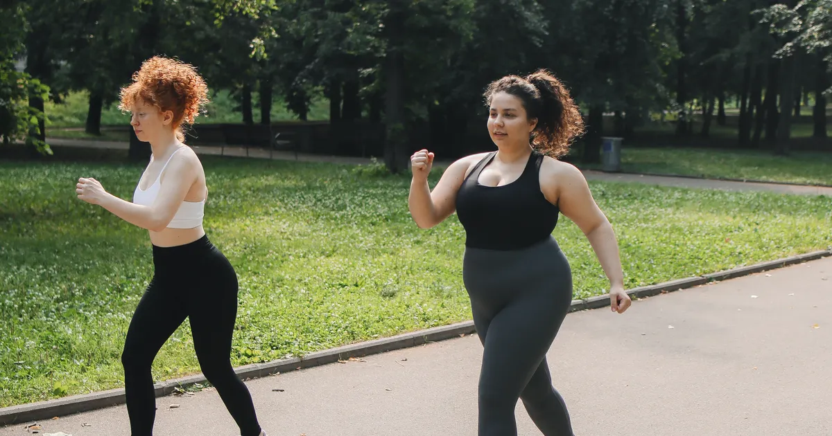 Two women walking briskly together on a park path