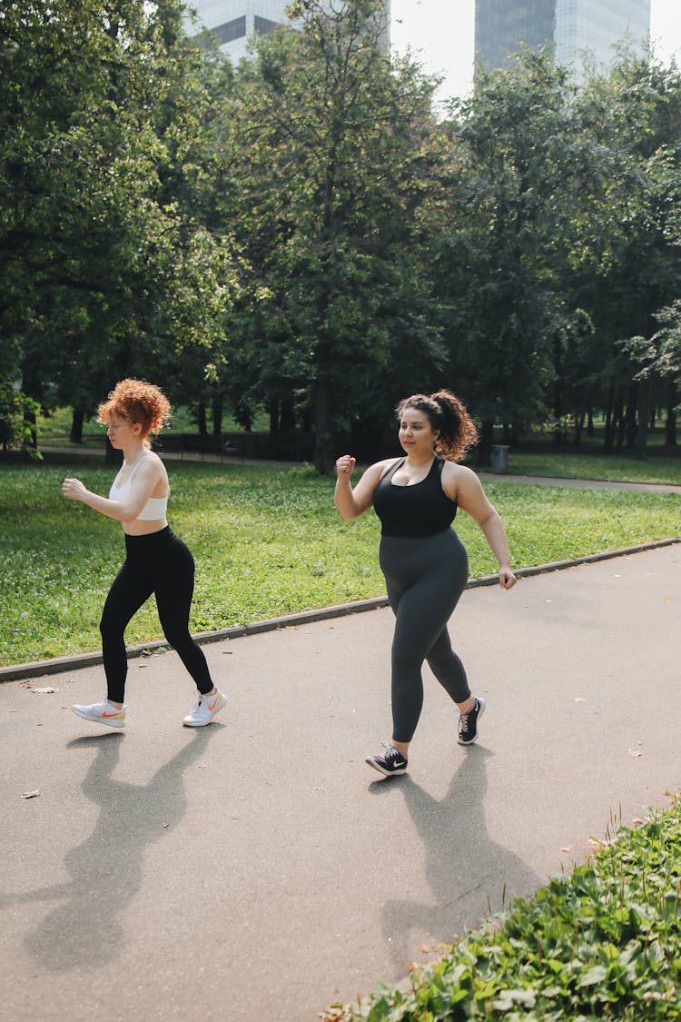 A Pair Of Women In Active Wear Brisk Walking On Walkway