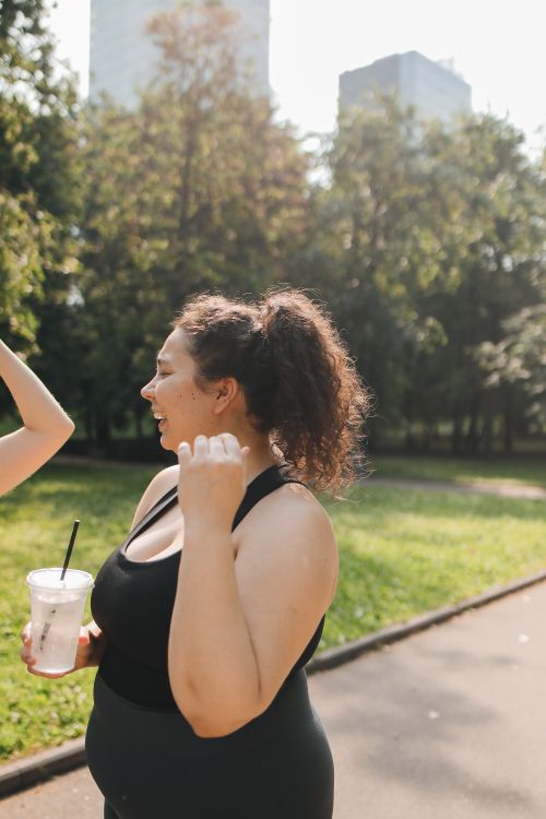 Free Smiling plus-size woman with curly hair in sporty attire enjoying a sunny day at the park. Stock Photo