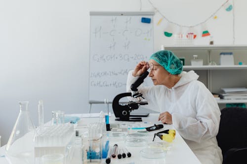Free Woman Looking through a Microscope Stock Photo