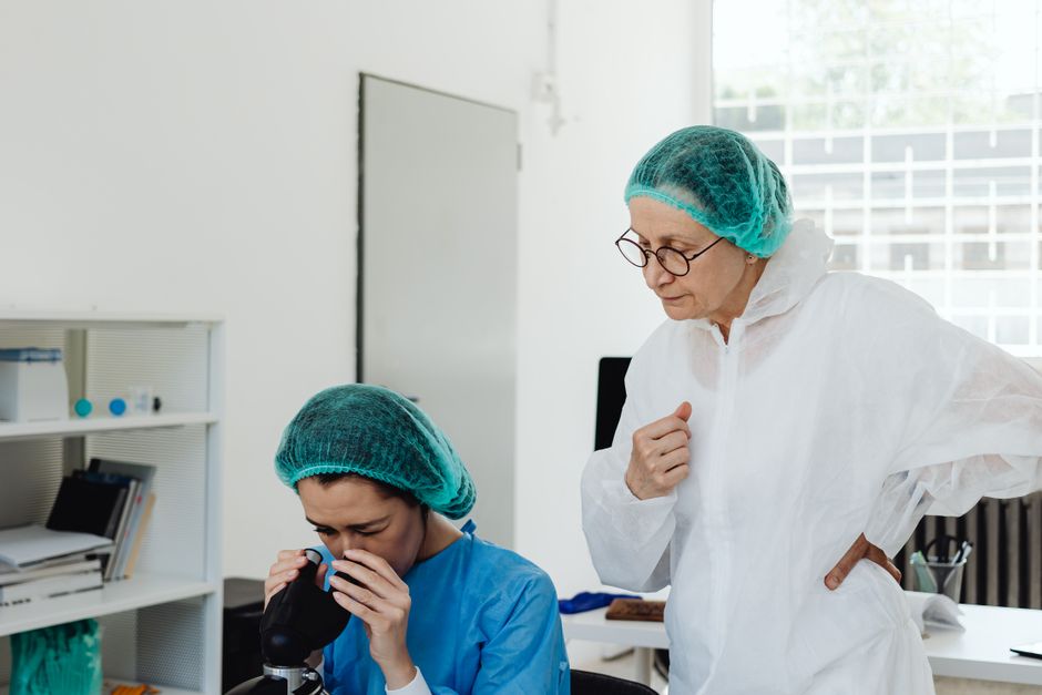 Researchers examining samples through a microscope in a laboratory — representing the multi-receptor pharmacology of ibogaine