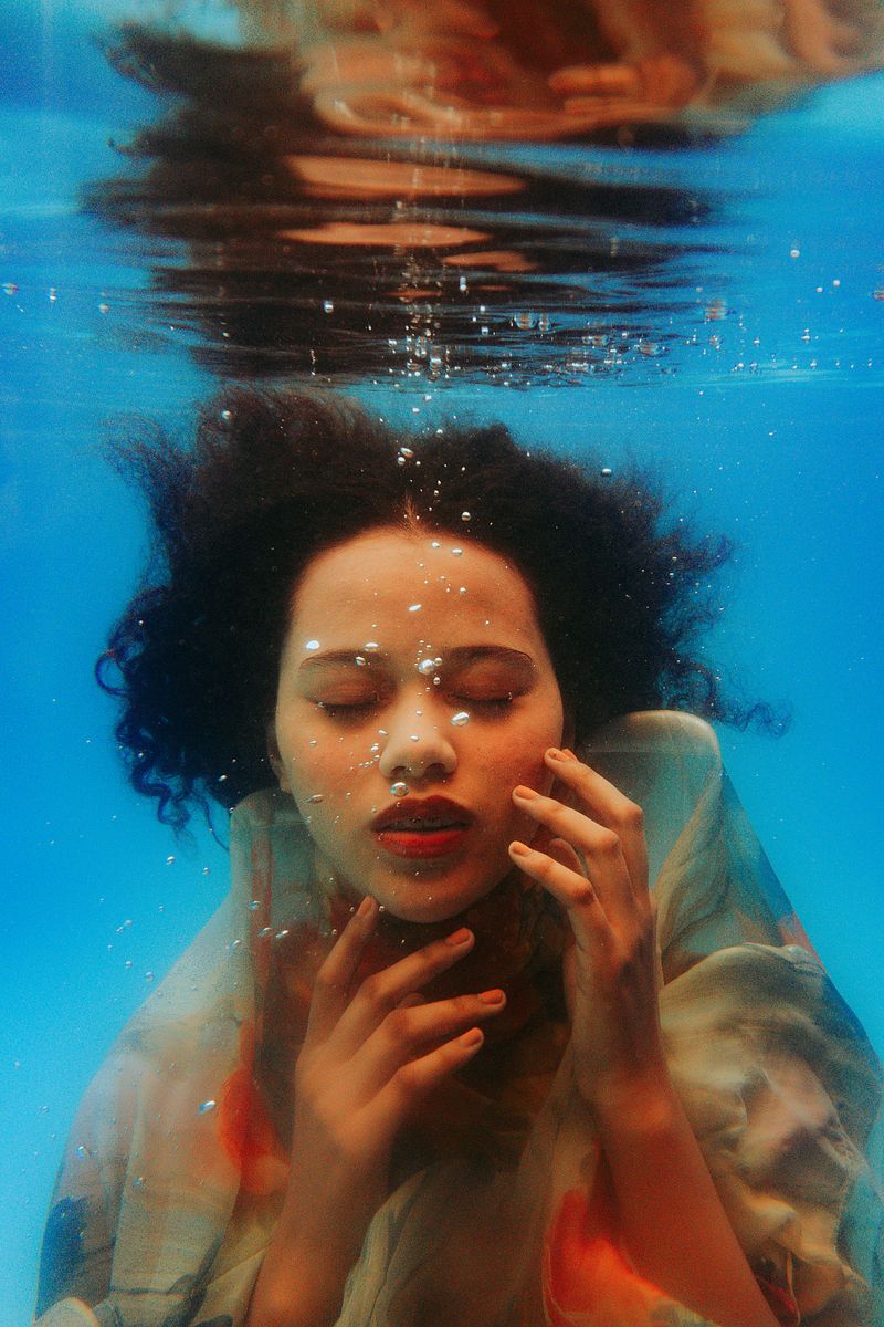 Calm close-up portrait of a woman with eyes closed under water, face relaxed