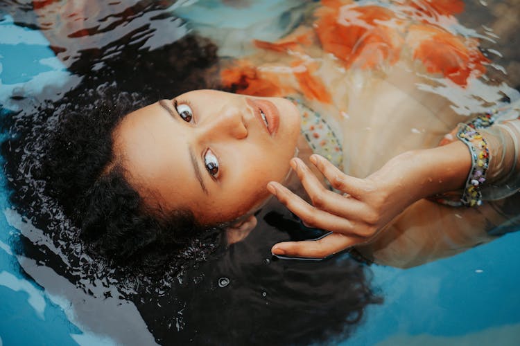 Close-Up Photo Of A Woman With Curly Hair Floating On A Pool