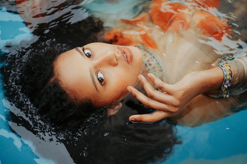 Free A calm woman with curly hair floats in a pool, exuding tranquility and beauty. Stock Photo