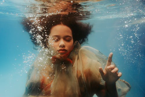Free Curly Haired Woman Under the Water with her Eyes Closed  Stock Photo