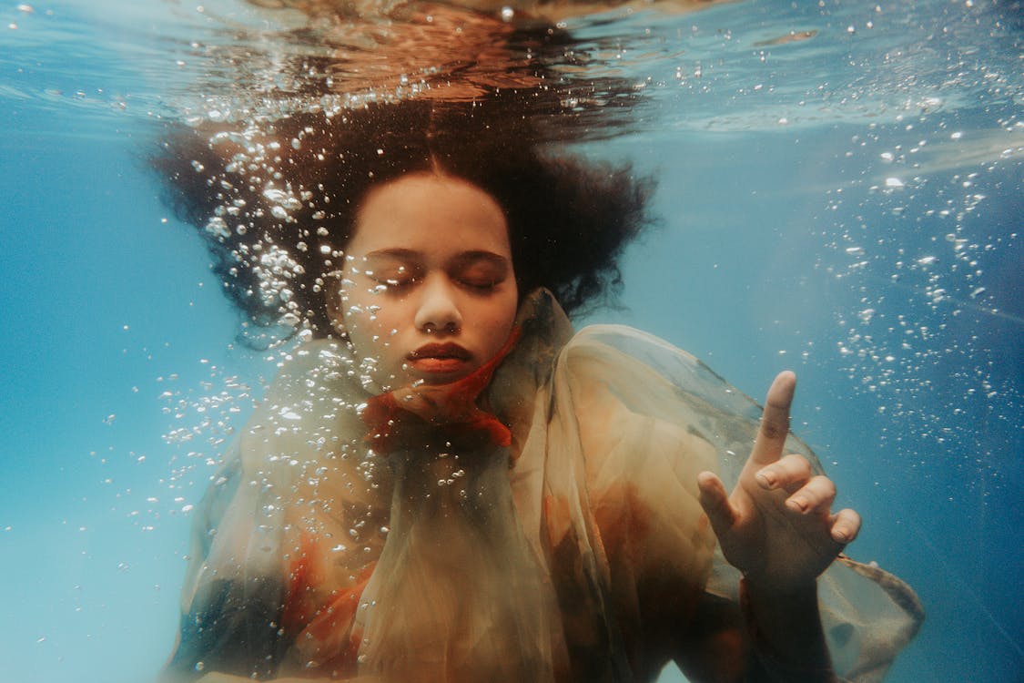 Curly Haired Woman Under the Water with her Eyes Closed 
