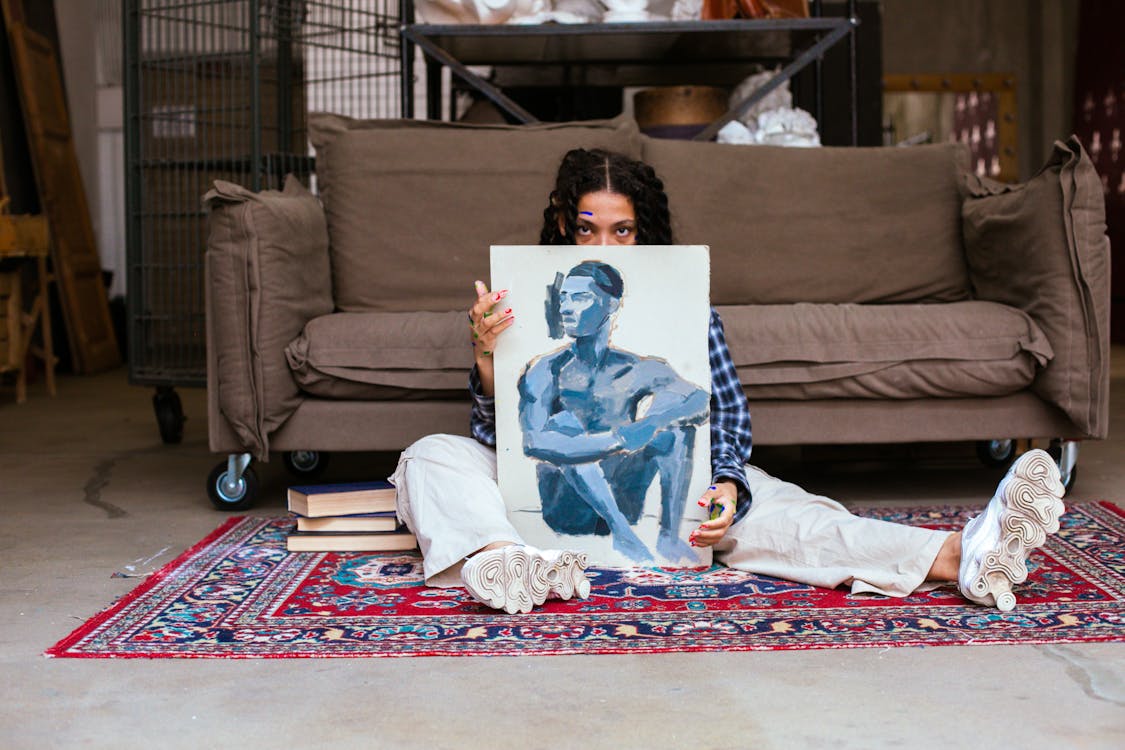 Woman Sitting on the Floor while Holding an Artwork