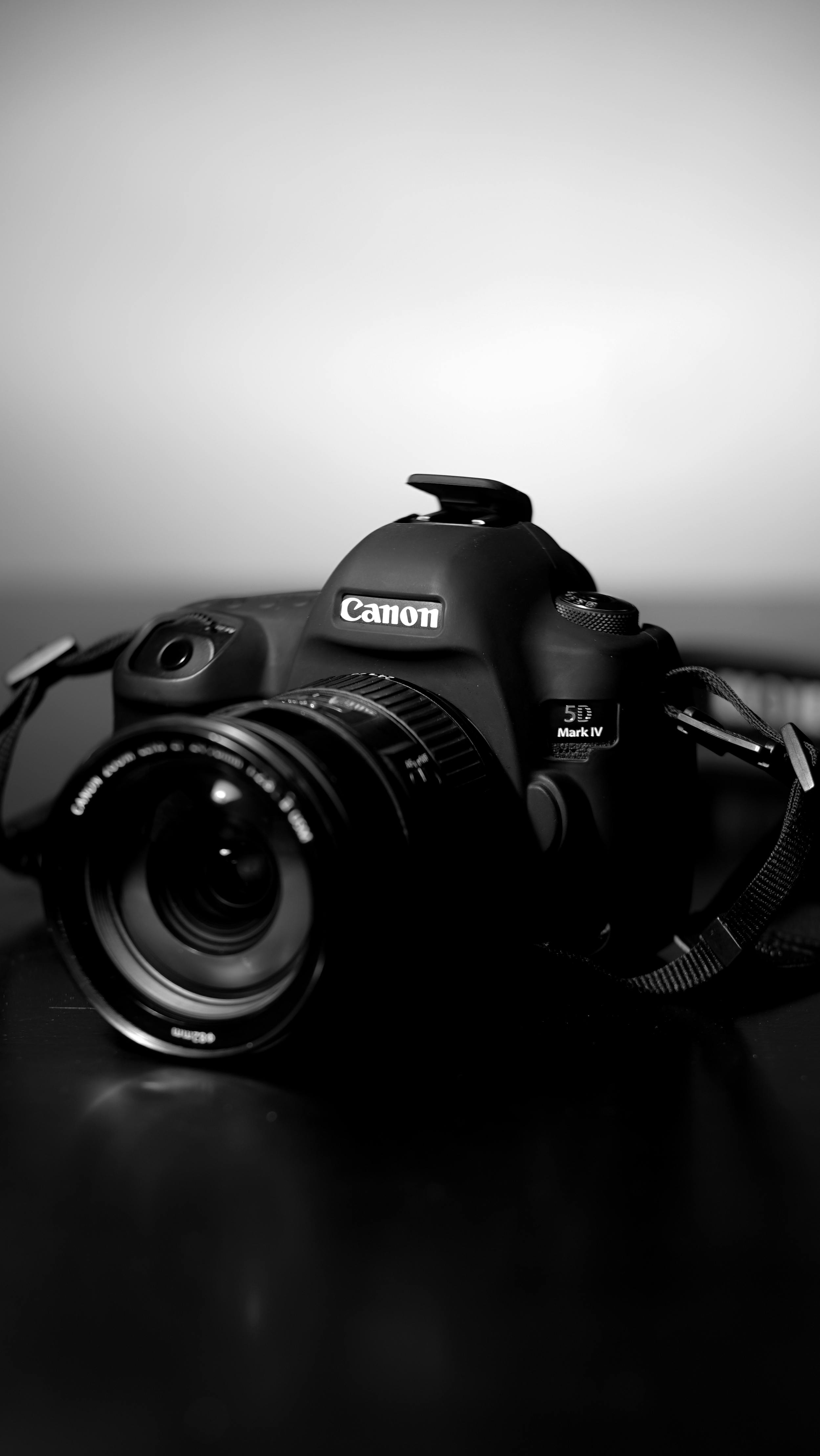 Free Artistic black and white photo of a DSLR camera on a table. Stock Photo