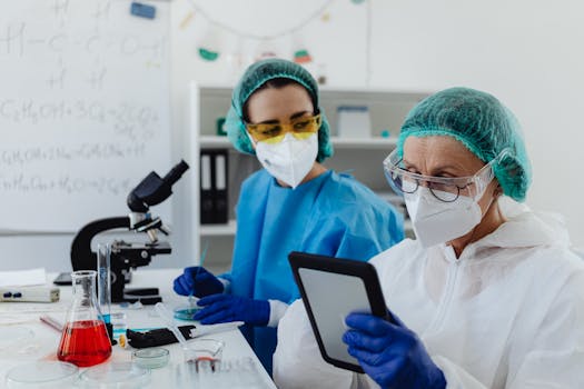 Two female scientists working in a lab, wearing protective gear and analyzing data.