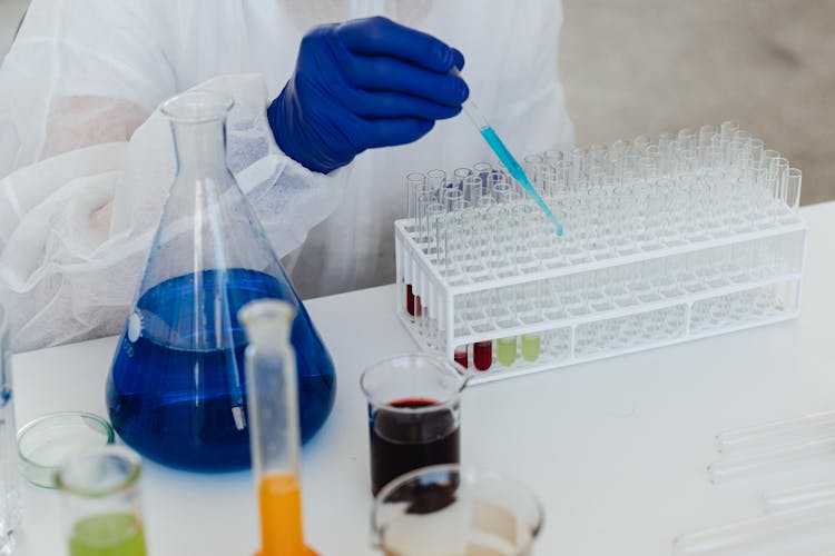 Hand Of A Person Holding A Dropper Over Test Tubes