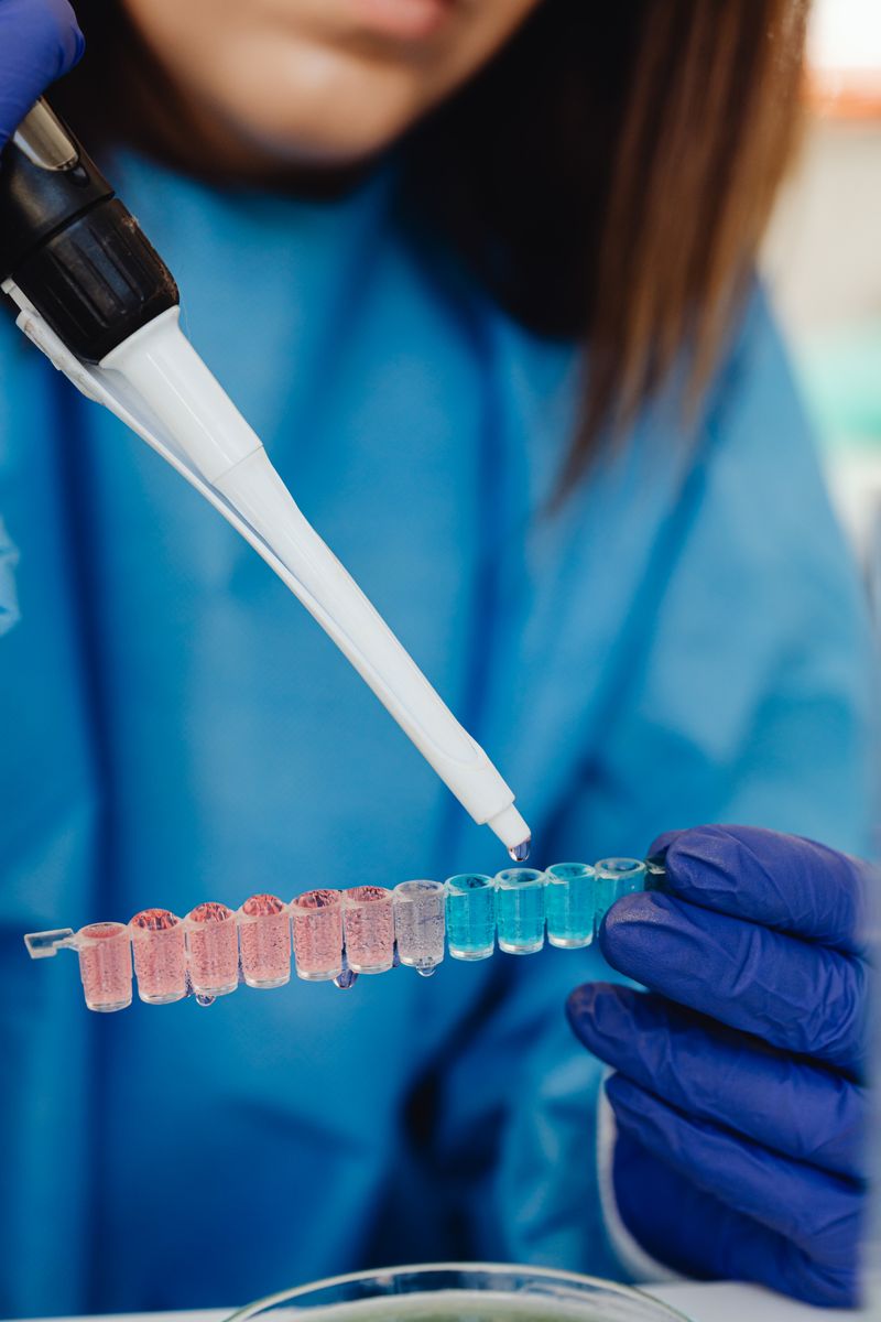 Scientist in blue gloves working with pipette and vials in laboratory experiment setting.