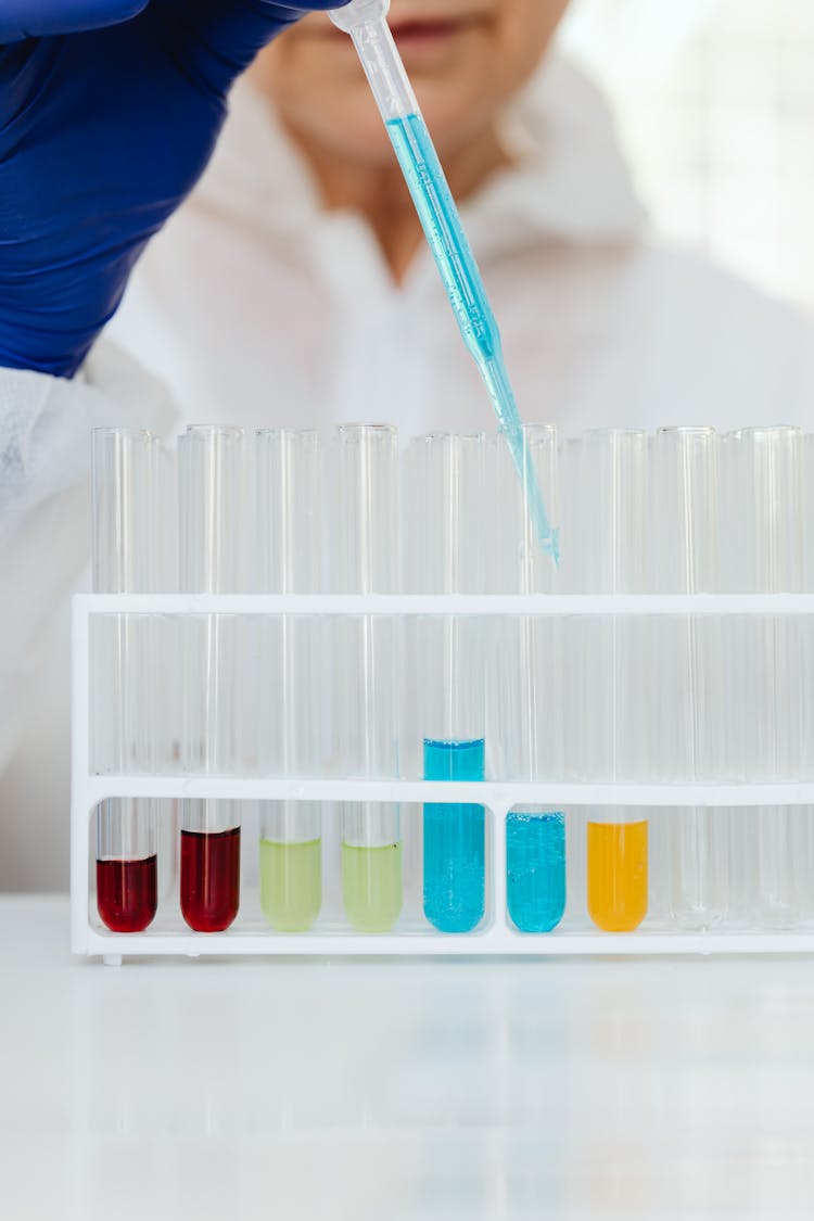 Person Putting Blue Liquid Into A Test Tube