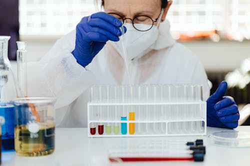 Woman Holding Clear Plastic Dropper Into Clear Glass Test Tubes