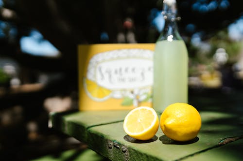 Slices of Lemon Near a Bottle With Lemonade on a Wooden Surface