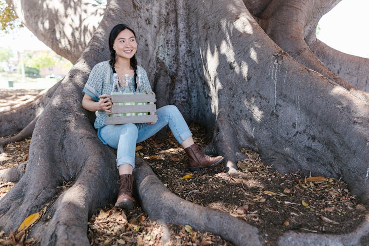 Woman Holding A Wooden Crate Sitting On Tree Roots