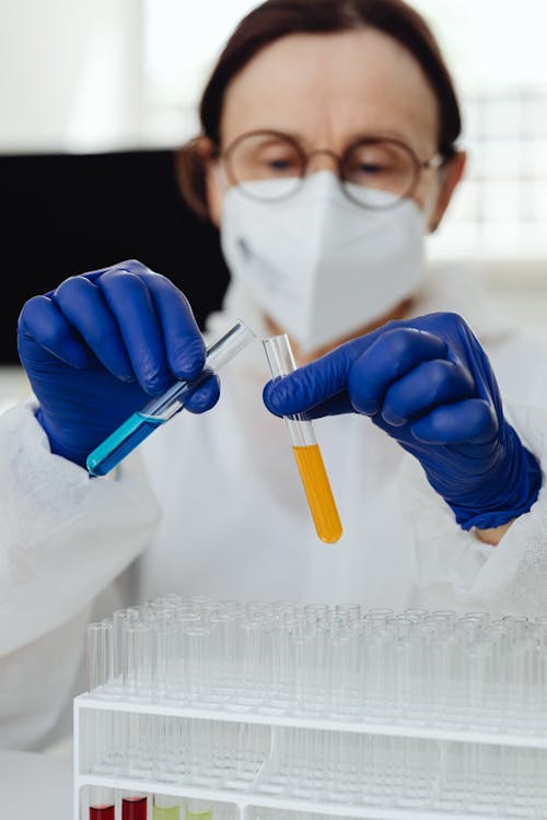Woman in Blue Gloves Holding Test Tubes