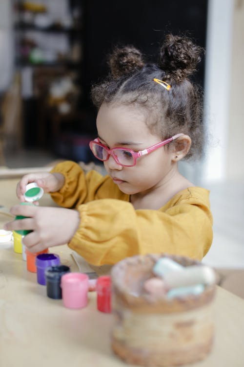 A Girl in Yellow Sweater Holding a Small Plastic Containers