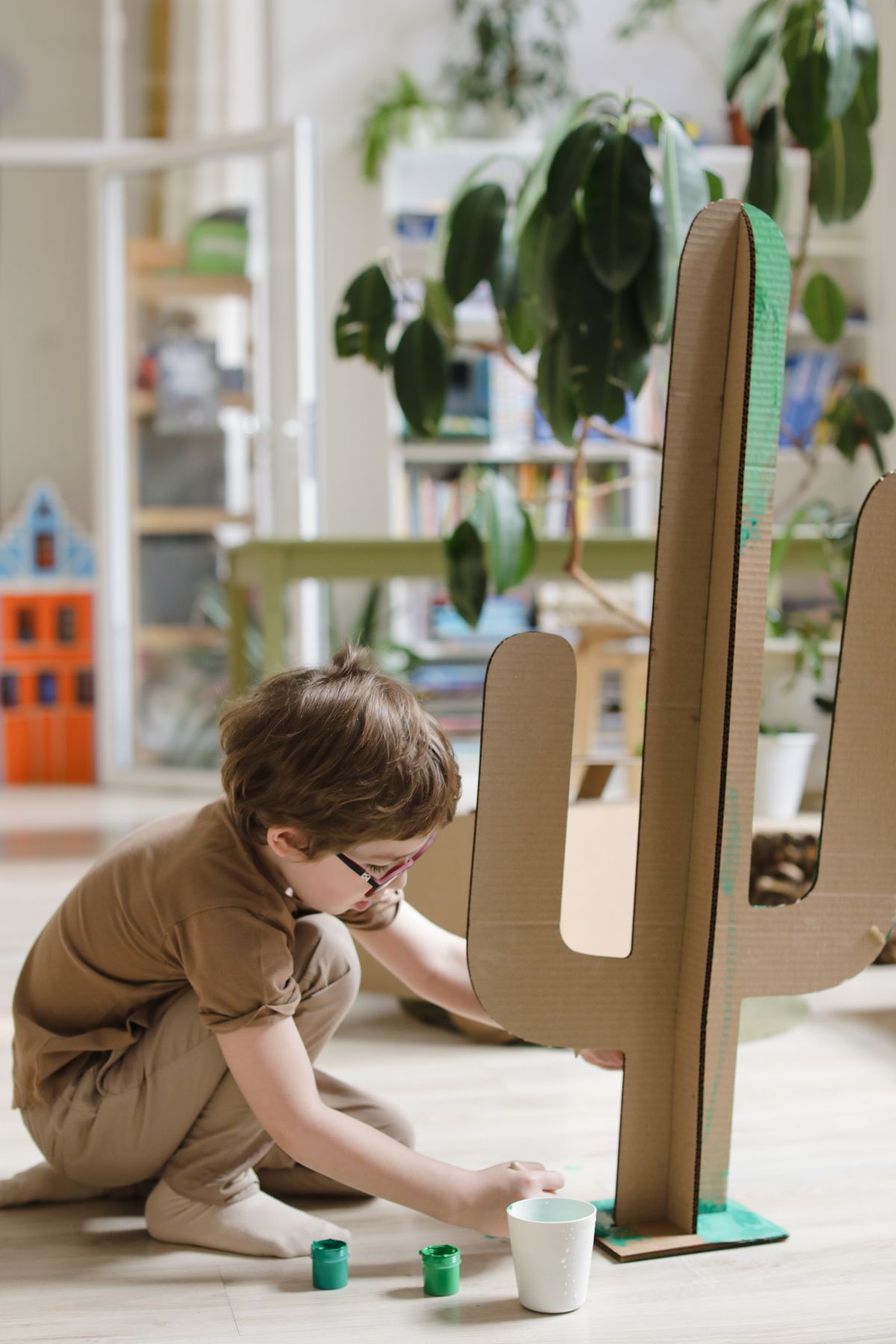 A young boy painting and building with cardboard at a cozy craft table