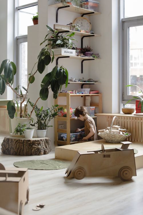 Free Child playing in a bright playroom with toys and plants. Stock Photo