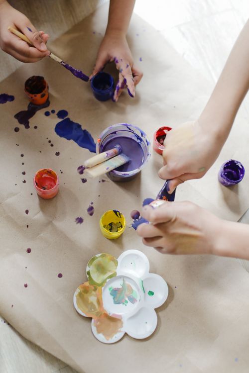 Free Overhead view of children painting with colorful paints, showcasing creativity and fun. Stock Photo