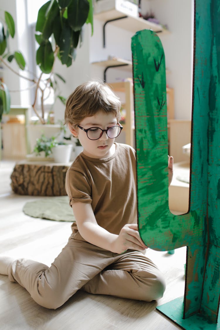 A Young Boy In Brown Shirt Sitting On The Floor While Painting