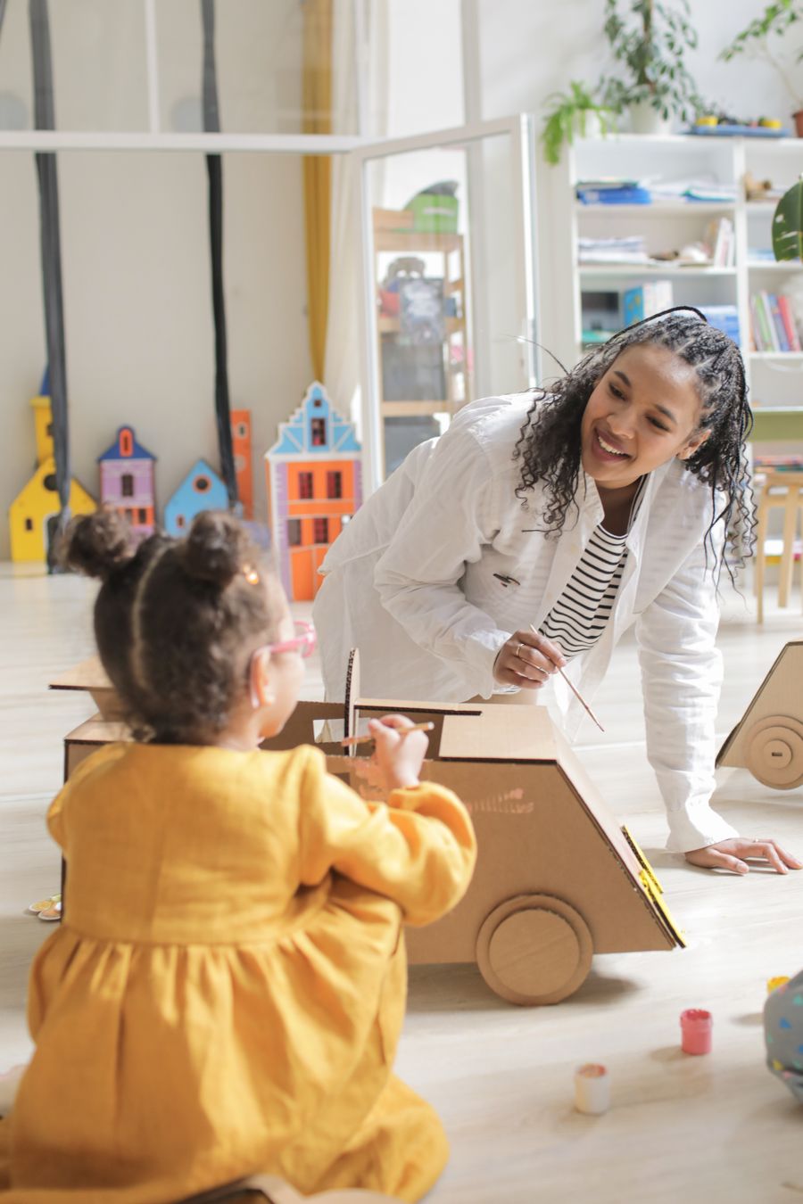 Educator and child engaging with creative materials indoors