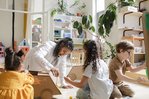 Kids Painting Cardboard Box with their Teacher