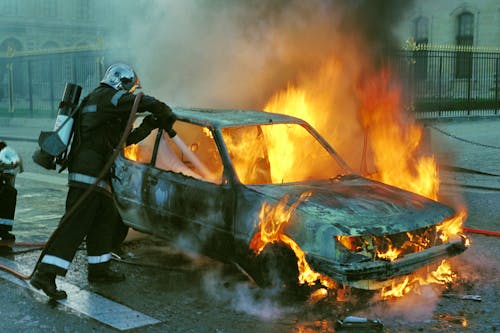 Free Firefighter Extinguishing a Burning Car Stock Photo