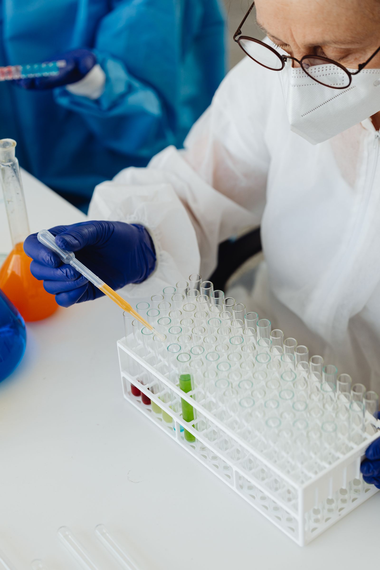 Professionista con protezioni utilizza una pipetta accanto alle provette.