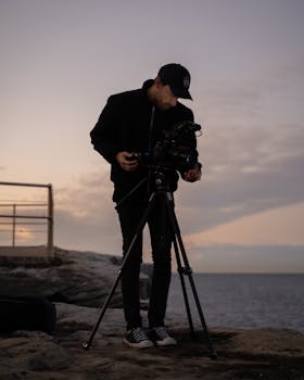 A photographer sets up his camera and tripod during sunset at Bondi Beach, Australia.