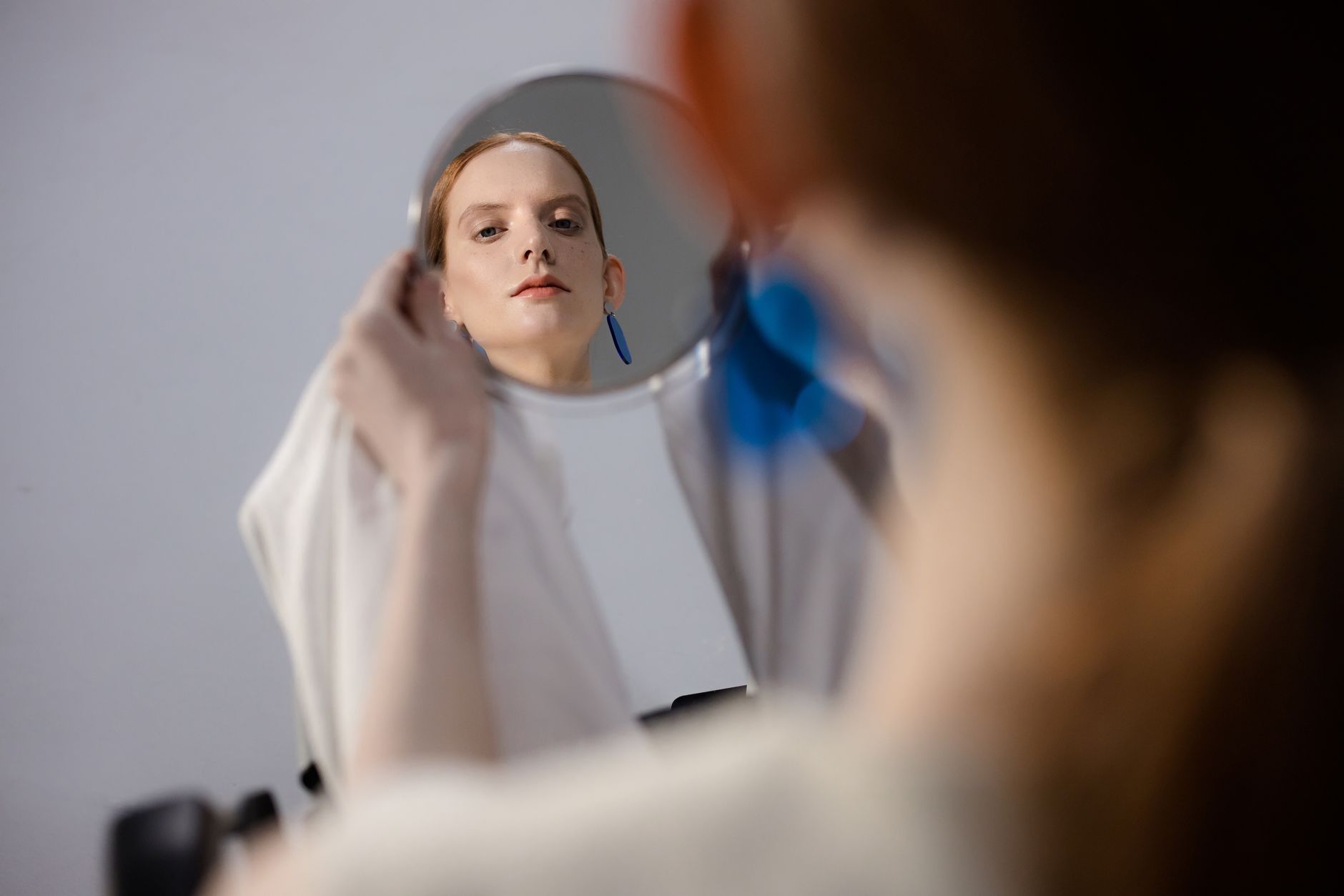 A woman studying her reflection, the kind of private moment before edited beauty becomes a goal.