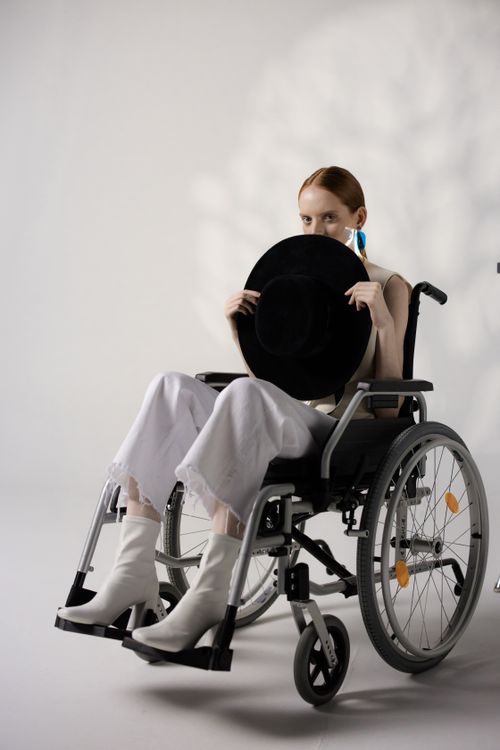 Free Stylish young woman in a wheelchair holding a hat, showcasing disability and fashion. Stock Photo