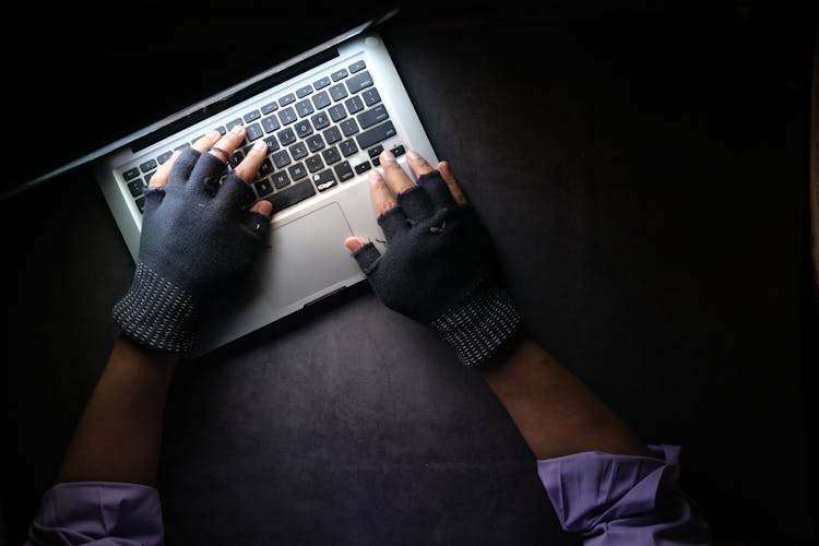 A Person Typing On Laptop While Wearing A Fingerless Gloves