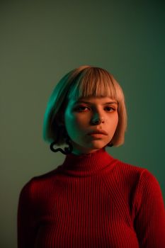 Studio portrait of young woman in red turtleneck sweater with dramatic lighting.