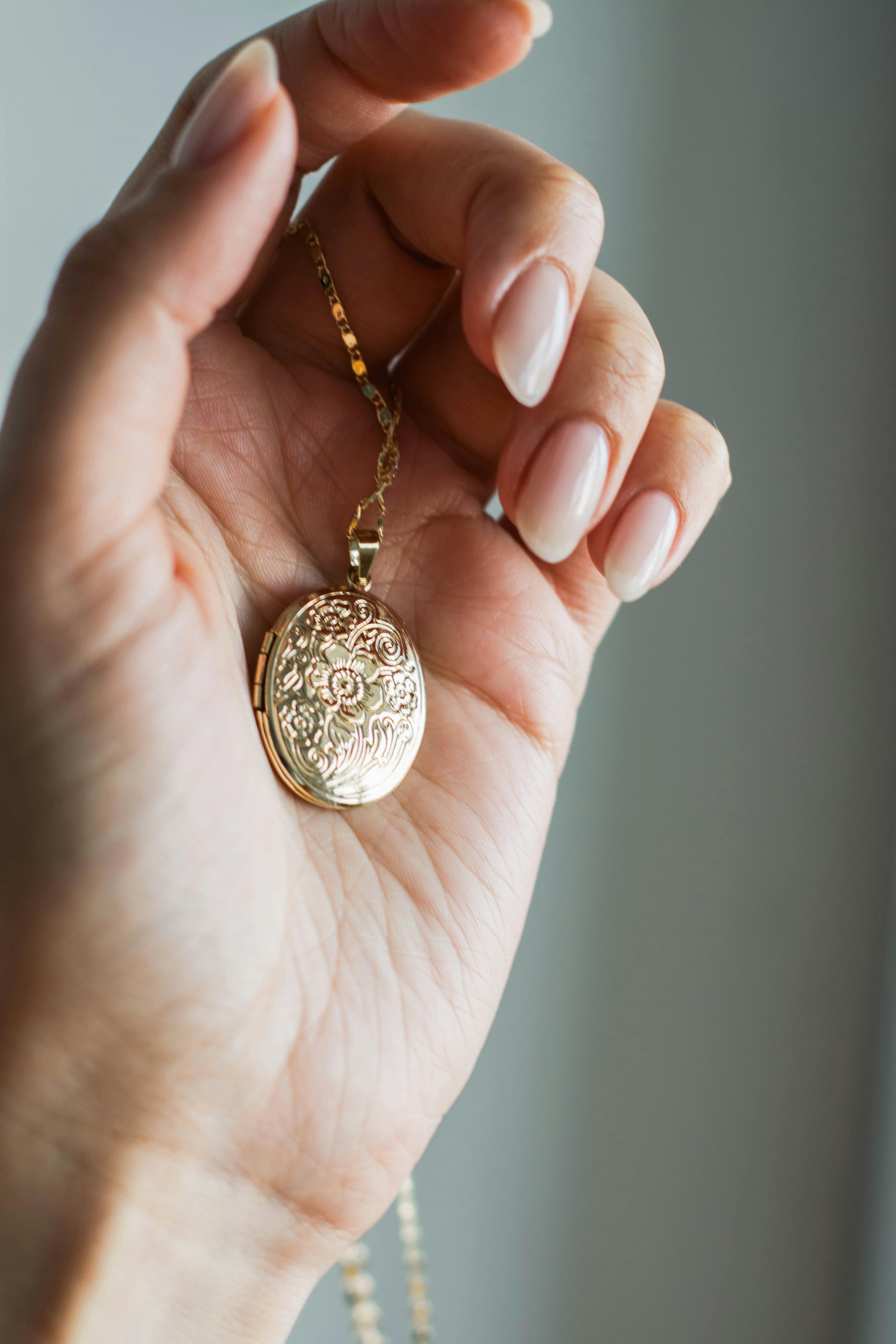 close up shot of a person holding a gold pendant